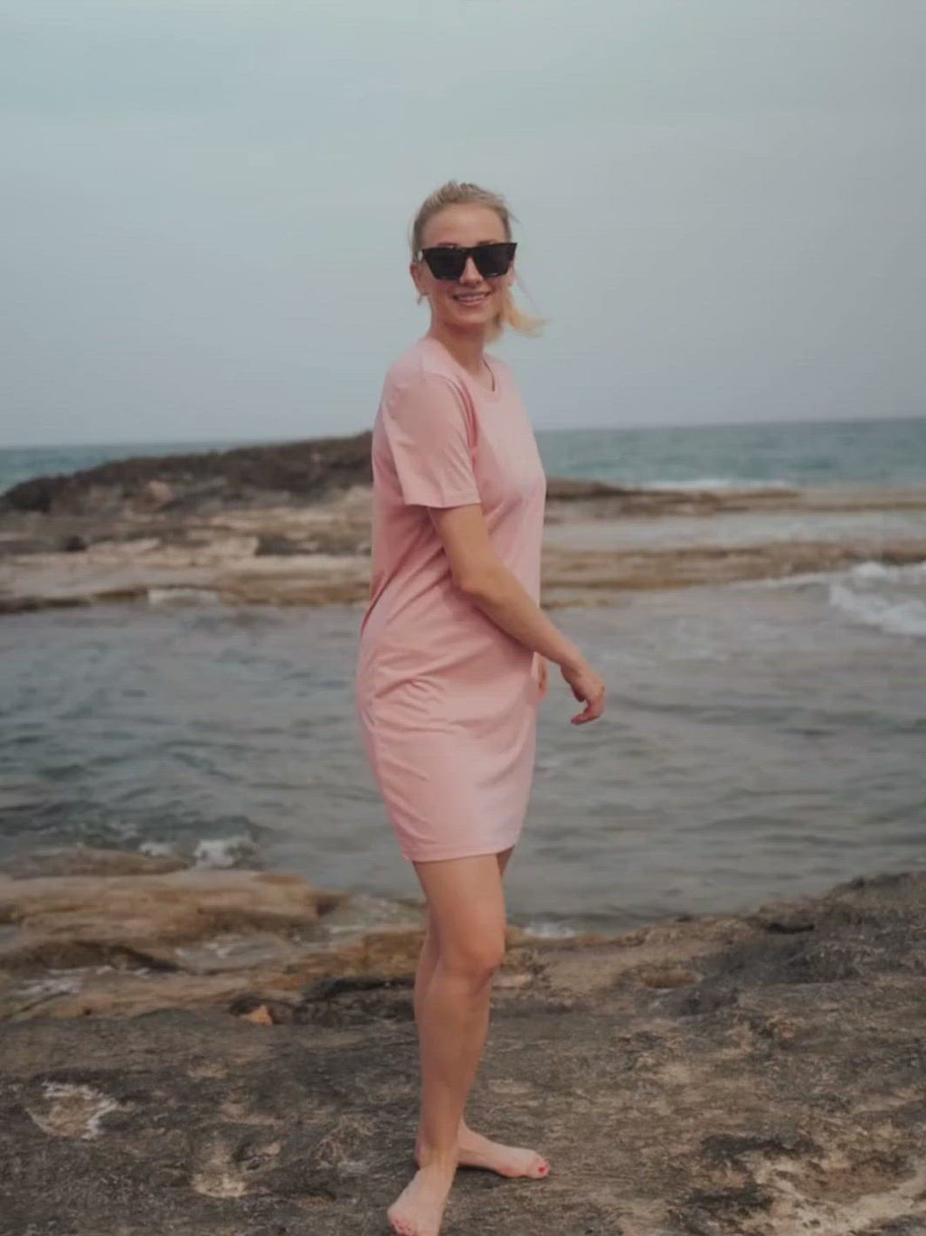 Marbella dámské letní šaty z biobavlny růžové kulatý výstřih s rukávy žena se otáčí na útesu u moře