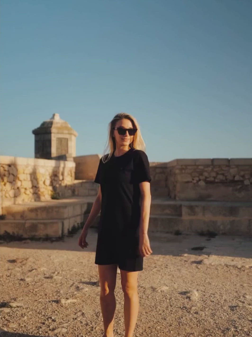 Marbella dámské letní šaty z biobavlny černé kulatý výstřih s rukávy žena se otáčí při západu slunce