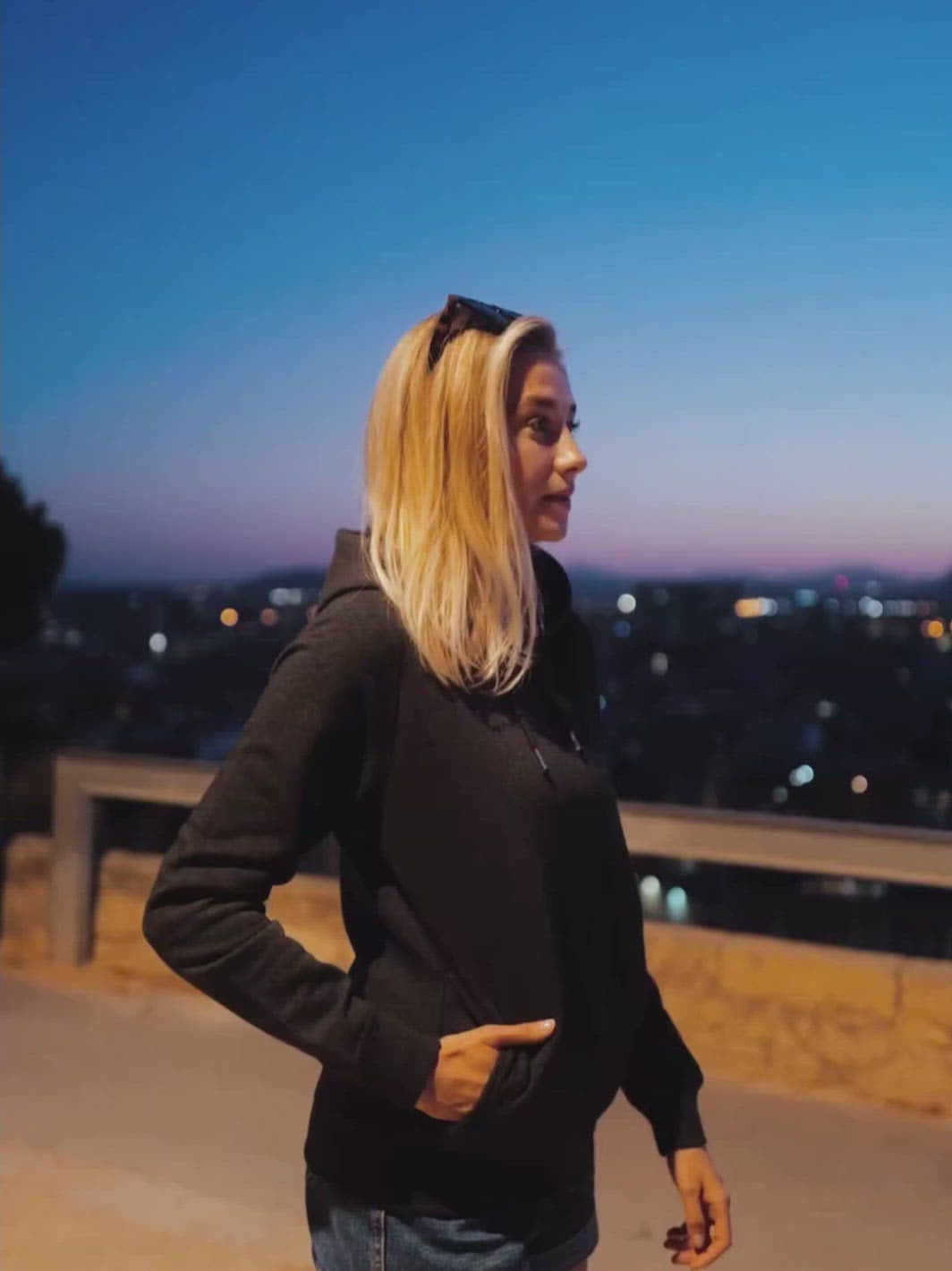 Side dámská mikina s kapucí a kapsami z biobavlny černá žíhaná žena v noci s rukama v kapse nad městem