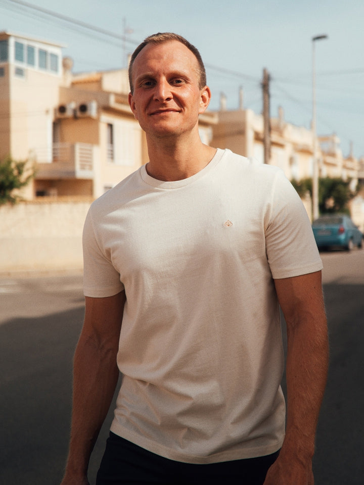 Feel pánské tričko z biobavlny s kulatým výstřihem přírodní nebarvené muž jde s úsměvem po ulici