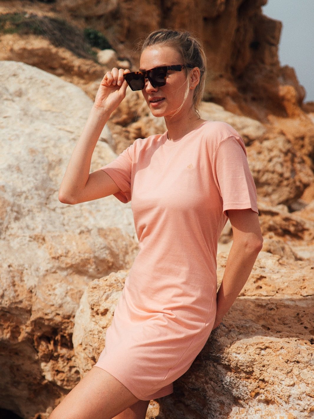 Marbella dámské letní šaty z biobavlny růžové kulatý výstřih s rukávy holka se opírá o útes na pláži