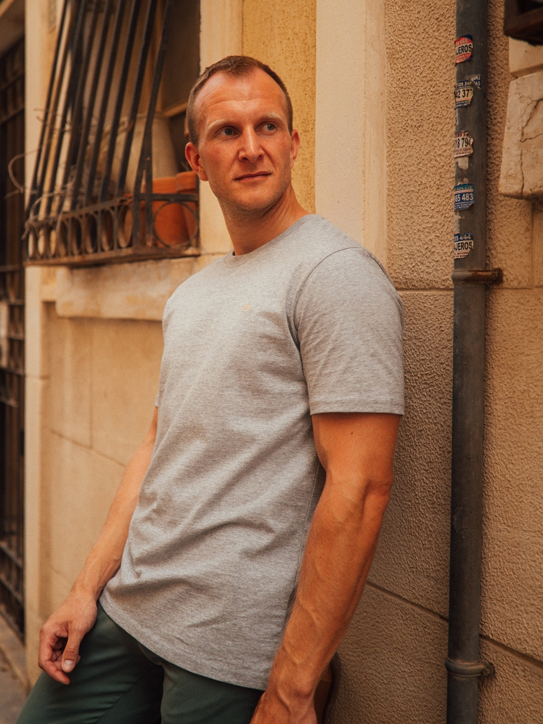 Royal pánské tričko z biobavlny vysoká gramáž šedé muž se opírá o dům